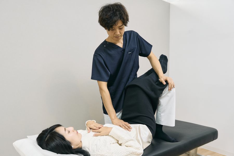 仰向けの状態で身体を丁寧に整える院長